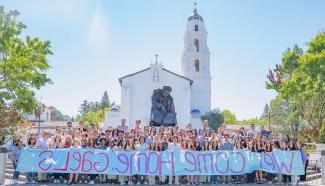 Students in front of SMC Chapel with sign WELCOME HOME, GAELS